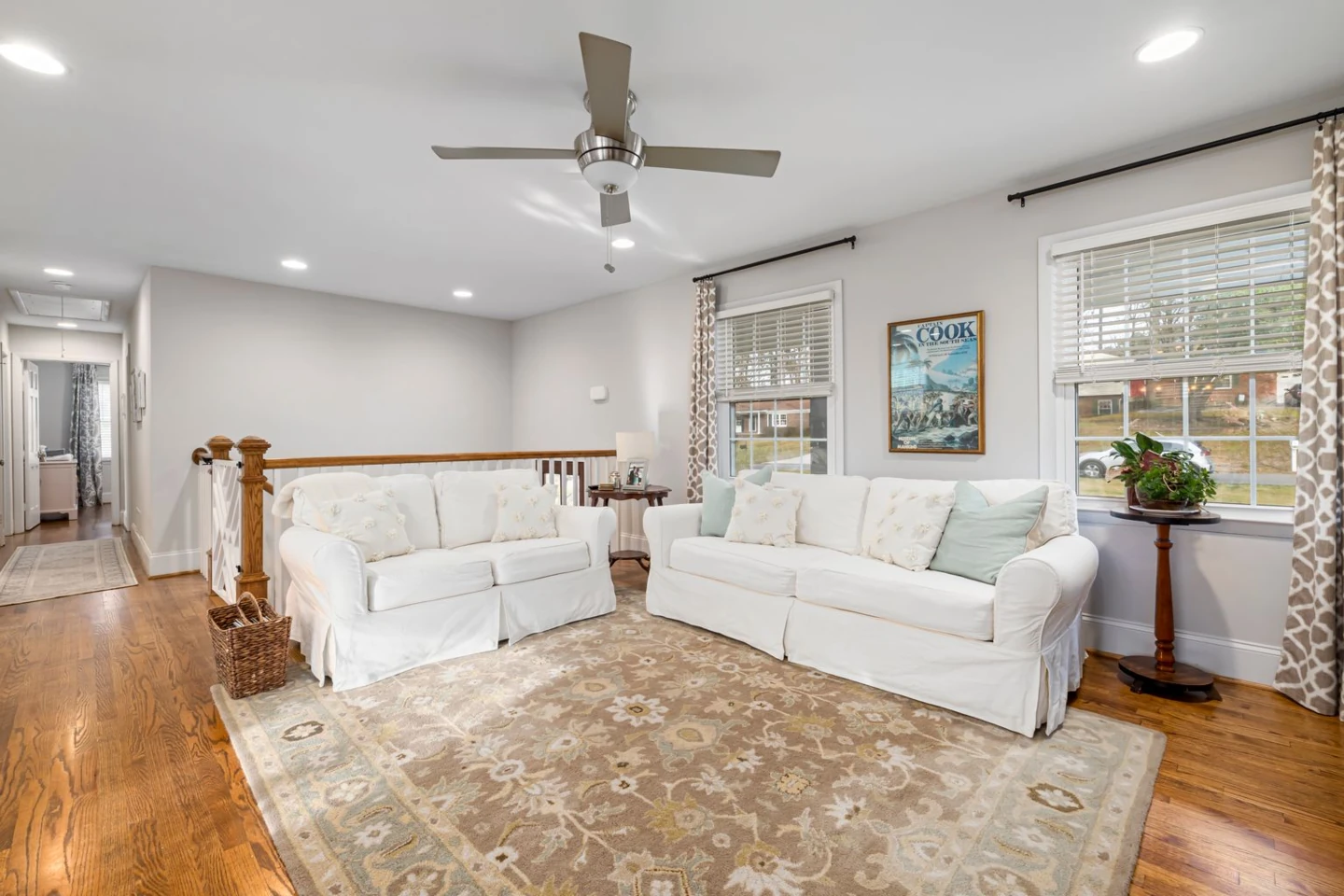 Real sitting room with white sofas, a patterned area rug and golden wood flooring