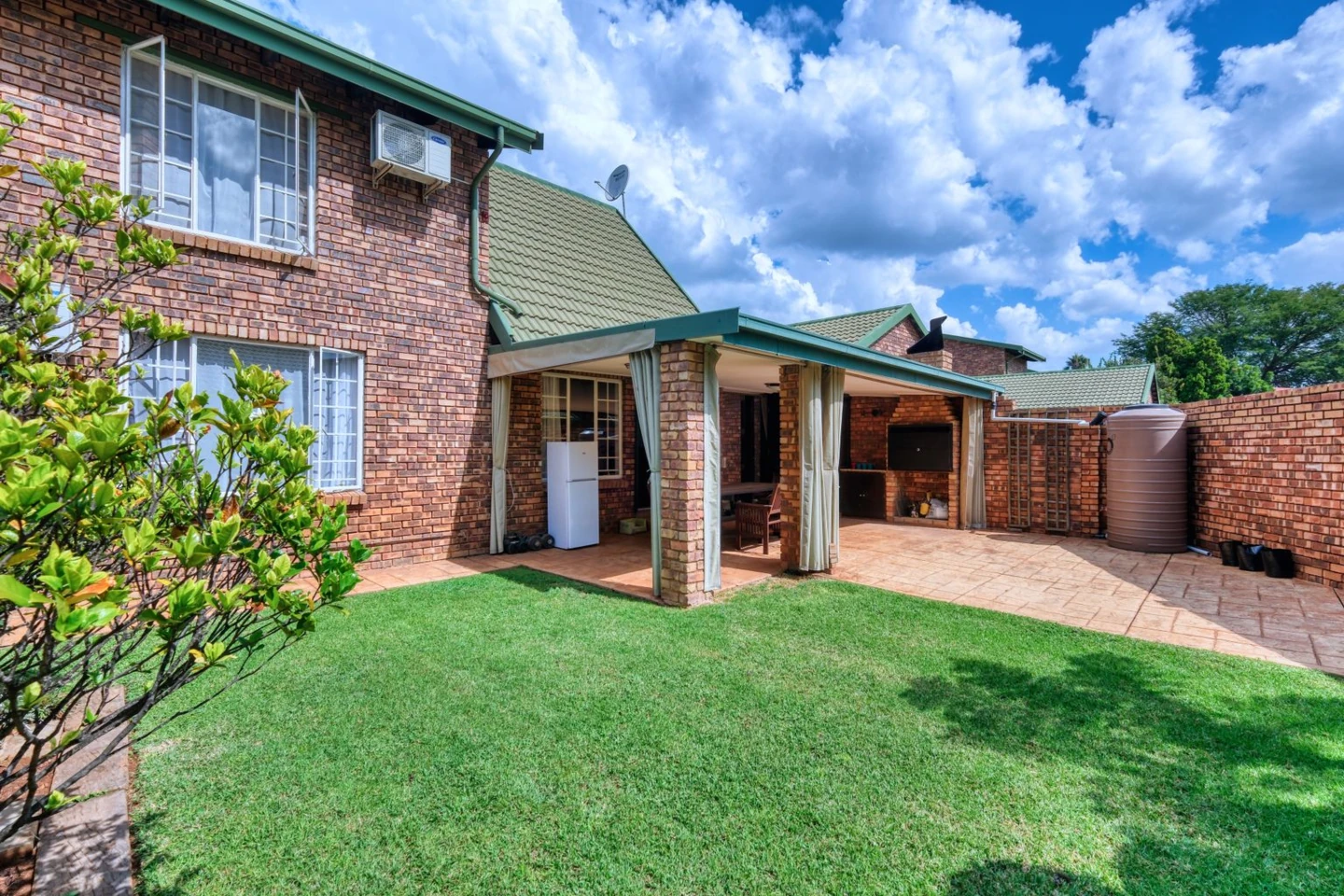 Original lawn and tiled patio outside a red brick home