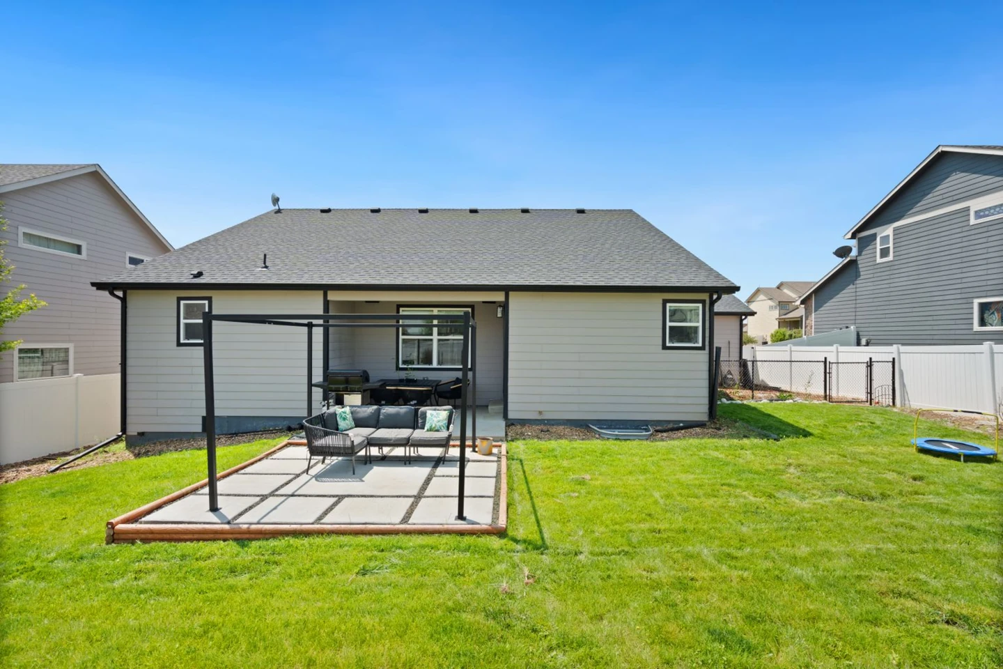 Real suburban backyard with a grass lawn beside a pergola patio