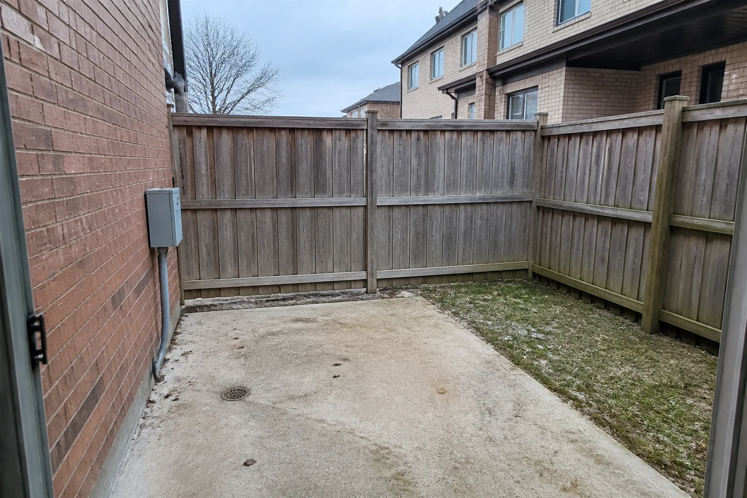 Empty concrete townhouse patio before a small courtyard landscape design